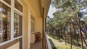 A balcony with a table and chairs, overlooking a forested area. - Tasteful Apartment | Balcony | 750 m to the beach (Łukęcin)