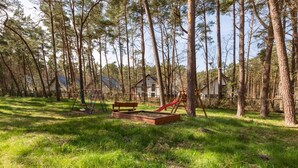 A forested area with a playground, including a slide and swings, and a bench. - Tasteful Apartment | Balcony | 750 m to the beach (Łukęcin)