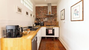 A compact kitchen with a brick wall, a coffee maker, a microwave, and a gas stove. - Luxury mansion loft by the beach (St kilda west)