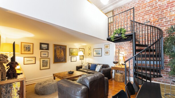 A cozy living room with a brick wall, a black spiral staircase, and a sofa set. - Luxury mansion loft by the beach (St kilda west)