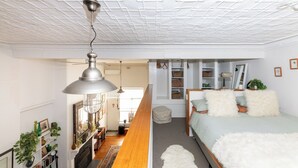 A bedroom with a wooden floor, a bed with white fluffy pillows, a white ceiling, and a hanging lamp. - Luxury mansion loft by the beach (St kilda west)