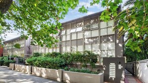A modern building with large windows and a landscaped area with bushes and trees. - Luxury mansion loft by the beach (St kilda west)
