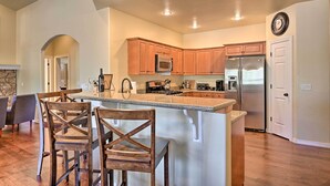 A modern kitchen with wooden cabinets, a stainless steel refrigerator, and a granite countertop. - 'Mount Elden Retreat:' 4 Mi to Downtown Flagstaff (Flagstaff)