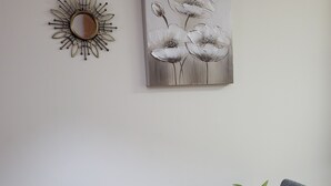 A dining area with a wooden table, a white vase with a plant, grey patterned cushions, and wall art of flowers. - Relaxing essence bass with private pool and patio! (Vera)