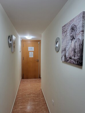 A hallway with a wooden door, a wall-mounted clock, and a Buddha statue. - Relaxing essence bass with private pool and patio! (Vera)