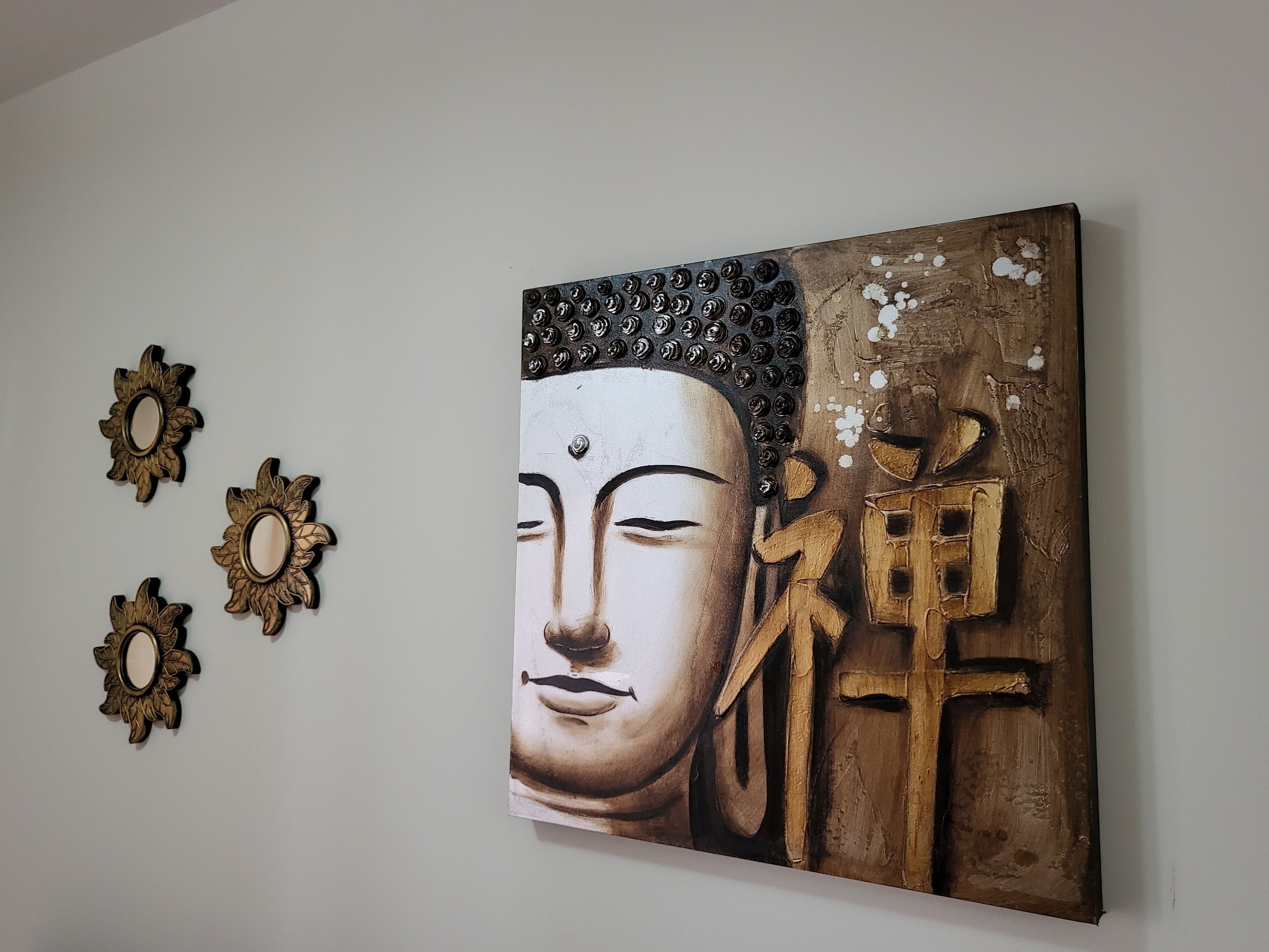 Un muro con un grande dipinto raffigurante Buddha e tre girasoli decorativi.