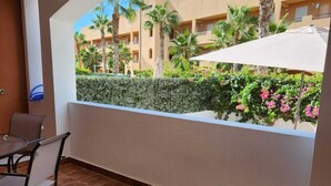 A balcony with a view of a building complex, a chair, and a table. - Relaxing essence bass with private pool and patio! (Vera)