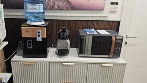 Pieni keittiönurkkaus, jossa on kahvinkeitin, vedenkeitin ja mikroaaltouuni yhdellä tasolla tai kaapissa.