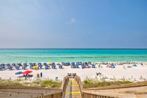 A wooden boardwalk leading to a beach with umbrellas and beach chairs. - Steps to Beach,Gulf Front Pool,Hot Tub-Vitamin Sea (Santa Rosa Beach)