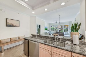 A modern kitchen with granite countertops, stainless steel appliances, and a view to the living area. - Steps to Beach,Gulf Front Pool,Hot Tub-Vitamin Sea (Santa Rosa Beach)
