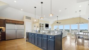 A spacious kitchen with a large island, wooden flooring, and pendant lighting. - Hatteras Retreat Oceanfront Home + Pets Stay Free (Buxton)