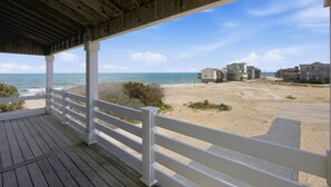 A wooden deck with white railings overlooking a sandy beach and ocean. - Hatteras Retreat Oceanfront Home + Pets Stay Free (Buxton)