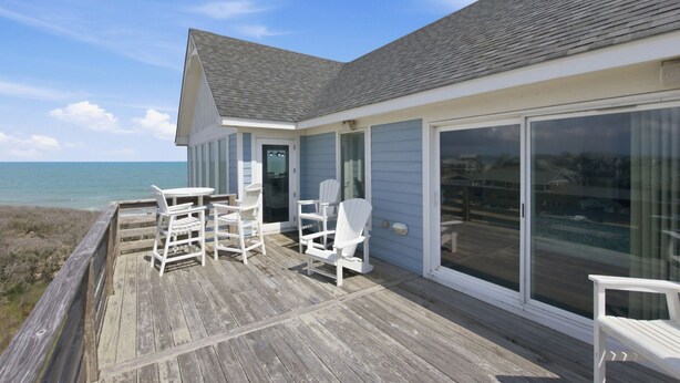 A beachfront property with a deck, chairs, and a view of the ocean. - Hatteras Retreat Oceanfront Home + Pets Stay Free (Buxton)
