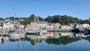 A harbor with boats docked, calm water, and buildings along the shore.