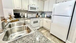A kitchen with white cabinets, a stainless steel sink, a microwave, an oven, and a refrigerator. - PCB - Marisol - Spring and Summer Dates Available!!  Discounted Rates!! (Panama City Beach)