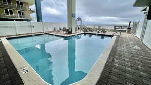 A swimming pool with a view of the ocean, surrounded by lounge chairs and a white fence. - PCB - Marisol - Spring and Summer Dates Available!!  Discounted Rates!! (Panama City Beach)