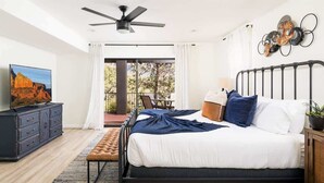 A bedroom with a bed, a television, a ceiling fan, a window, and a balcony. - Upscale Red Rock Retreat- Spa, Views, Pet Friendly (Sedona)