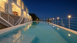 A swimming pool with a view of the sea at night, surrounded by a white railing and steps leading to a building. - Yeosu Nukim Poolvilla (Yeosu)