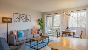 A modern living room with a sofa, coffee table, and dining area.