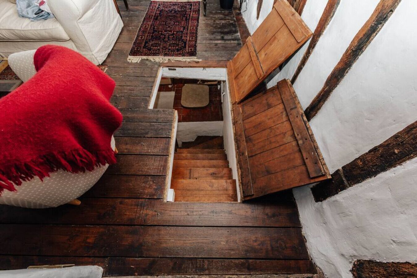 Un escalier étroit en bois, avec un petit banc en bois à sa base.
