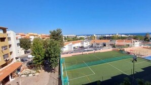 Un terrain de sport avec un filet, entouré de bâtiments et sous un ciel dégagé.