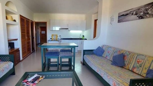 Un espace de vie compact comprenant une kitchenette, un coin repas et deux canapés.