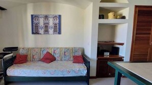 Une pièce comprenant un canapé, une petite table, un meuble et une porte.
