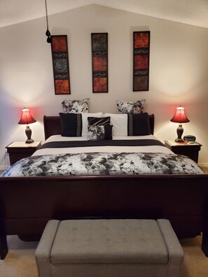 Une chambre à coucher bien aménagée, avec un grand lit, deux tables de chevet et trois œuvres d’art accrochées au mur.