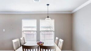 A dining area with a table and chairs, two windows with blinds, a hanging light fixture, and a patterned rug. - Sleeps 10*Pet Friendly*Kid Friendly*Near Dallas  (Fate)