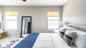 A bedroom with a bed, a ceiling fan, a window with blinds, a mirror, and a bedside table. - Sleeps 10*Pet Friendly*Kid Friendly*Near Dallas  (Fate)