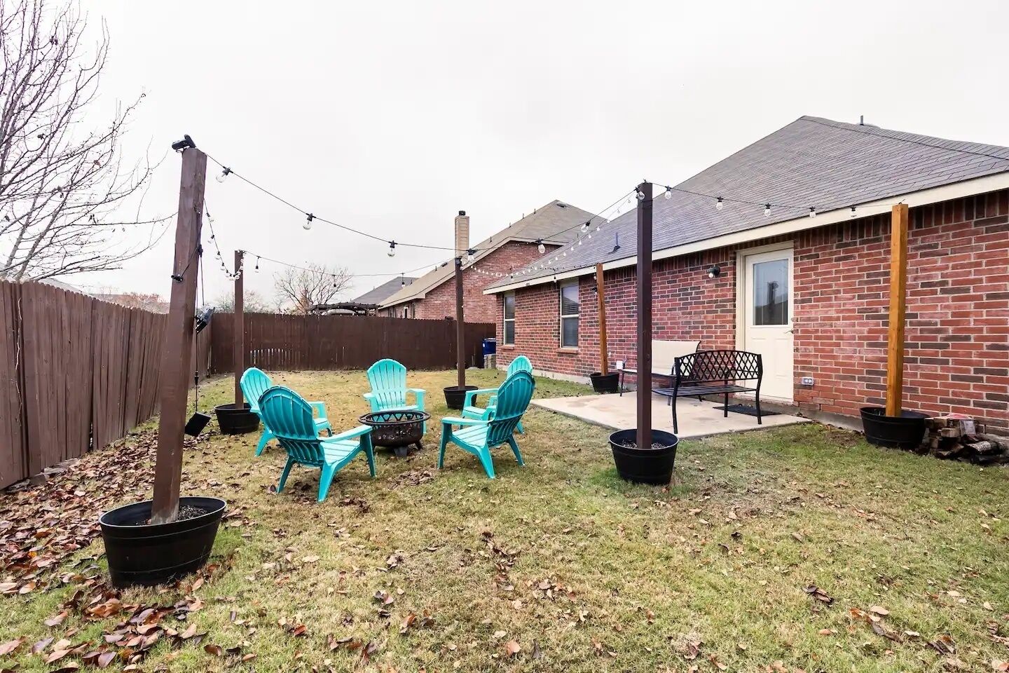 Een achtertuin met een huis van baksteen, een schommel en buitenmeubels.
