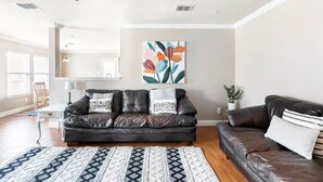 A living room with a dark leather sofa, a patterned rug, and a painting on the wall. - Sleeps 10*Pet Friendly*Kid Friendly*Near Dallas  (Fate)