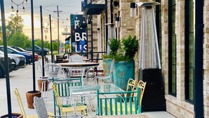 Outdoor seating with metal chairs and tables, a brick building, and a sign with partially visible letters. - Sleeps 10*Pet Friendly*Kid Friendly*Near Dallas  (Fate)