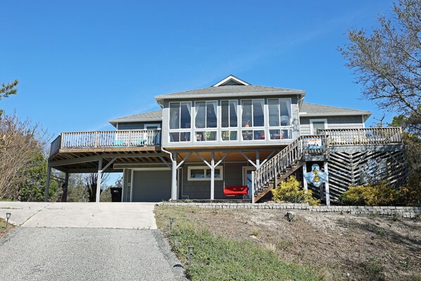 A two-story house with a balcony, a covered porch, and a small boat docked outside. - D116A- Oceanside - Duck - Saturday Check In! (Duck)