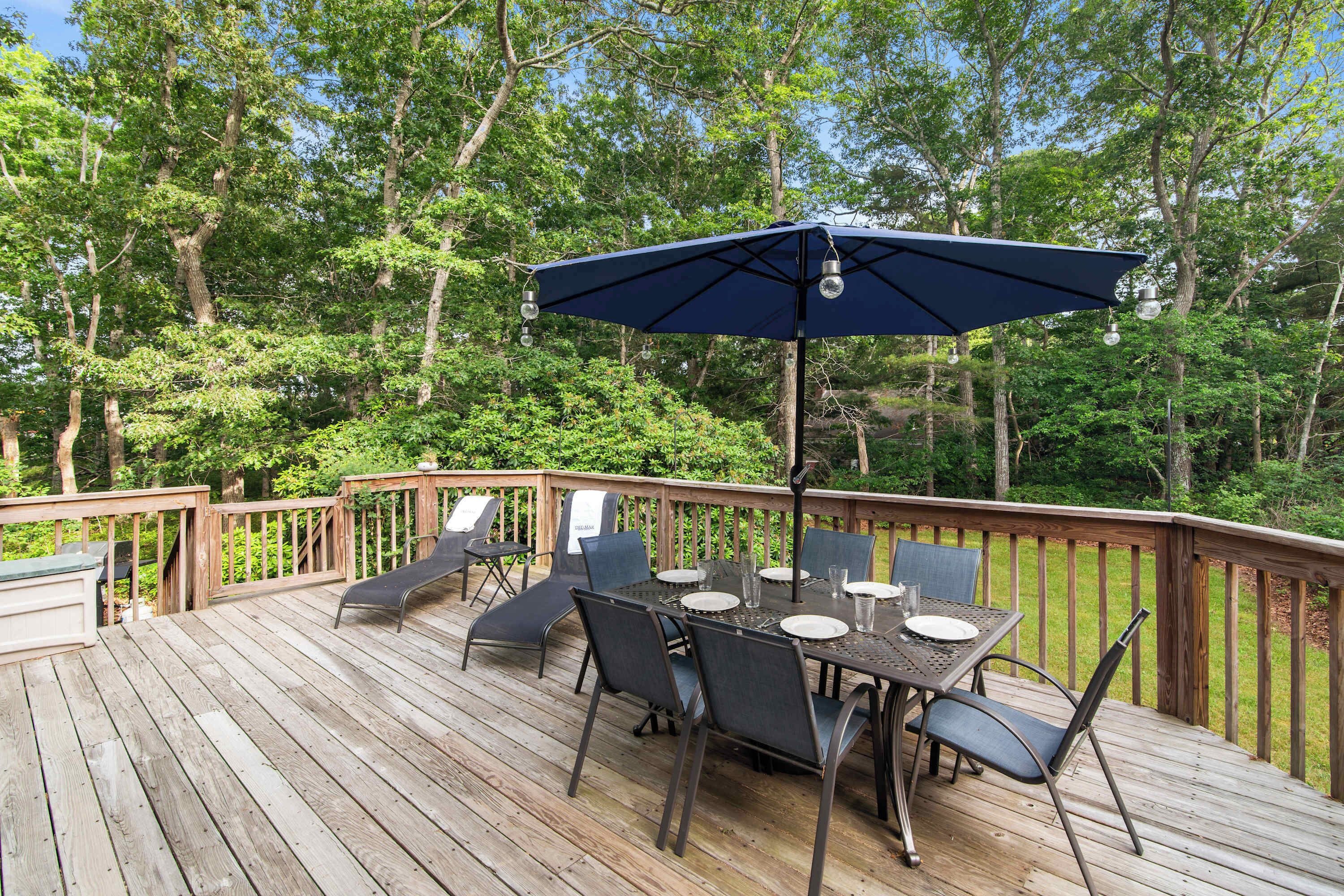 A wooden deck with a table and chairs, surrounded by trees.