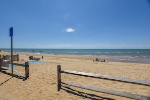A beach with a wooden fence, a blue sign, and the ocean in the background.