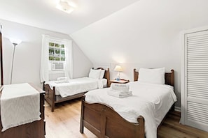 A room with two wooden beds, a nightstand with a lamp, a window with curtains, and a white wardrobe. - Minutes to Bayside Beaches, Dogs Welcome! (Eastham)