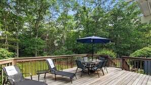 A wooden deck with a table and chairs, surrounded by trees.