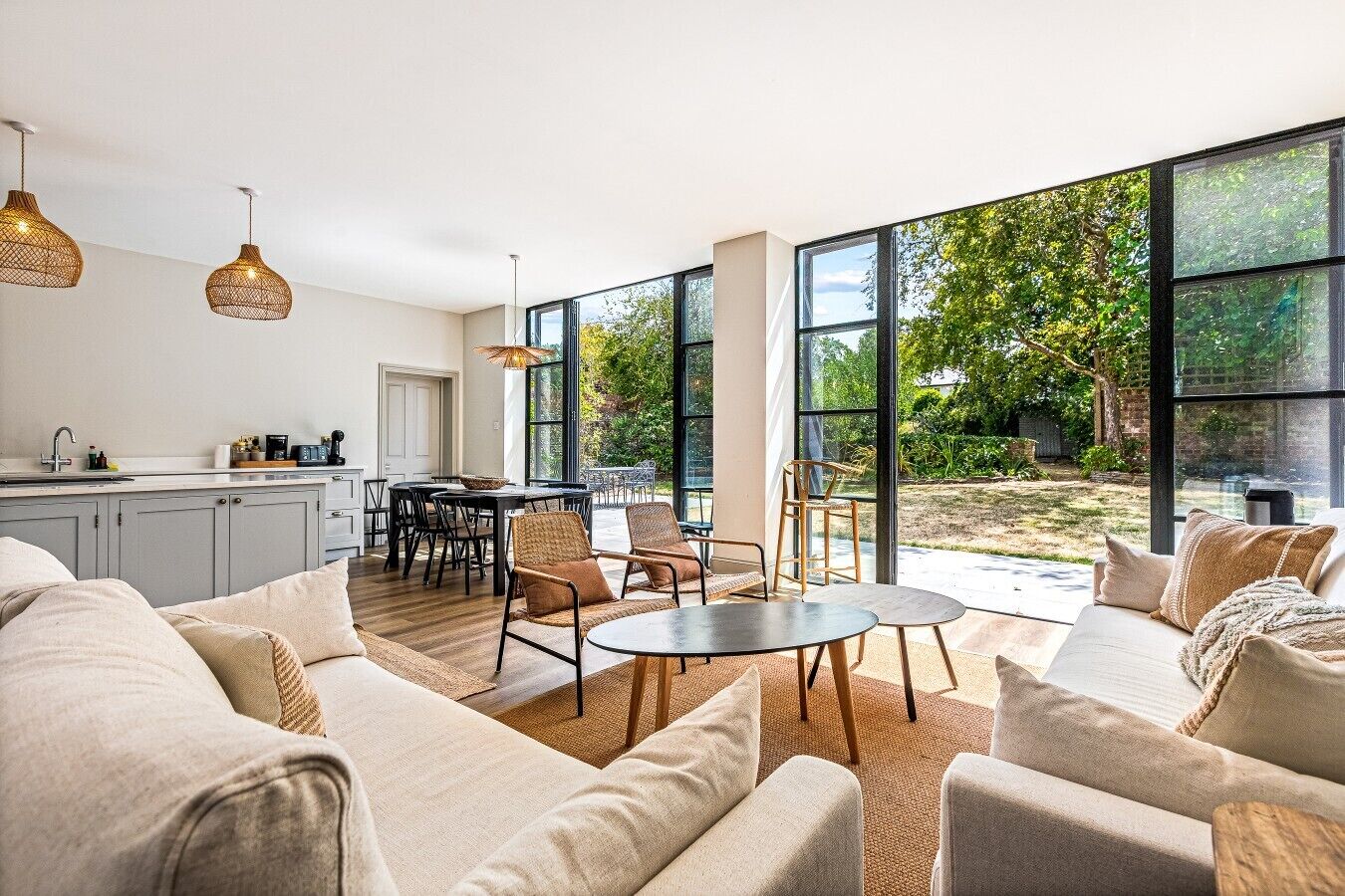 A modern living space with a kitchen, dining area, and large windows offering a view of the outdoors.