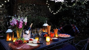 An outdoor dining setup with a variety of food and drinks, including a charcuterie board, cheeses, fruits, and a bottle of champagne. - Montpellier House, Centrally Located, Pet Friendly (Henley-On-Thames)