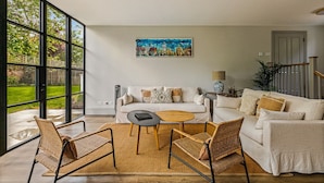 A spacious living room with a large window, a sofa set, a coffee table, and a painting on the wall. - Montpellier House, Centrally Located, Pet Friendly (Henley-On-Thames)