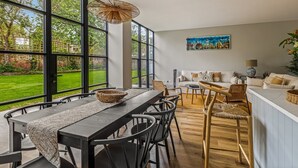 A modern kitchen with a dining area, large windows, and a view of a garden. - Montpellier House, Centrally Located, Pet Friendly (Henley-On-Thames)