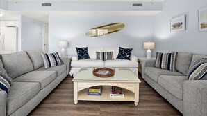 A living room with a sofa set, a coffee table, and a wall-mounted mirror. - Watch the Fireworks From Your Balcony!!! (Ocean City)
