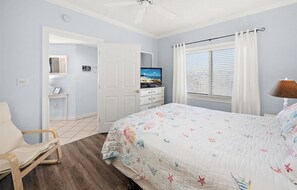 A bedroom with a bed, a chair, a TV, a ceiling fan, and a window with blinds. - Watch the Fireworks From Your Balcony!!! (Ocean City)