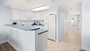 A modern kitchen with white cabinets, a central island, and a built-in microwave. - Watch the Fireworks From Your Balcony!!! (Ocean City)