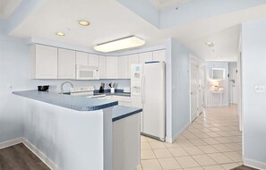 Una cocina moderna con armarios blancos, una isla central y un microondas integrado.