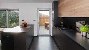 A modern kitchen with dark cabinetry, a wooden accent wall, and a view to a wooden deck. - Fr Dlant Mcmp525 in Fr Dlant nad Ostravic (Frydlant nad Ostravici)
