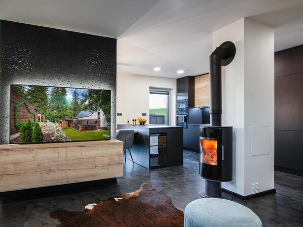 Una sala de estar moderna con chimenea, un banco de madera y un amplio ventanal con vistas a un jardín.
