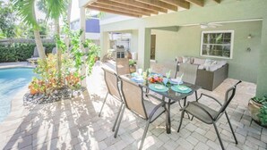 Um pátio externo com piscina, mesa de jantar, cadeiras e área de estar.