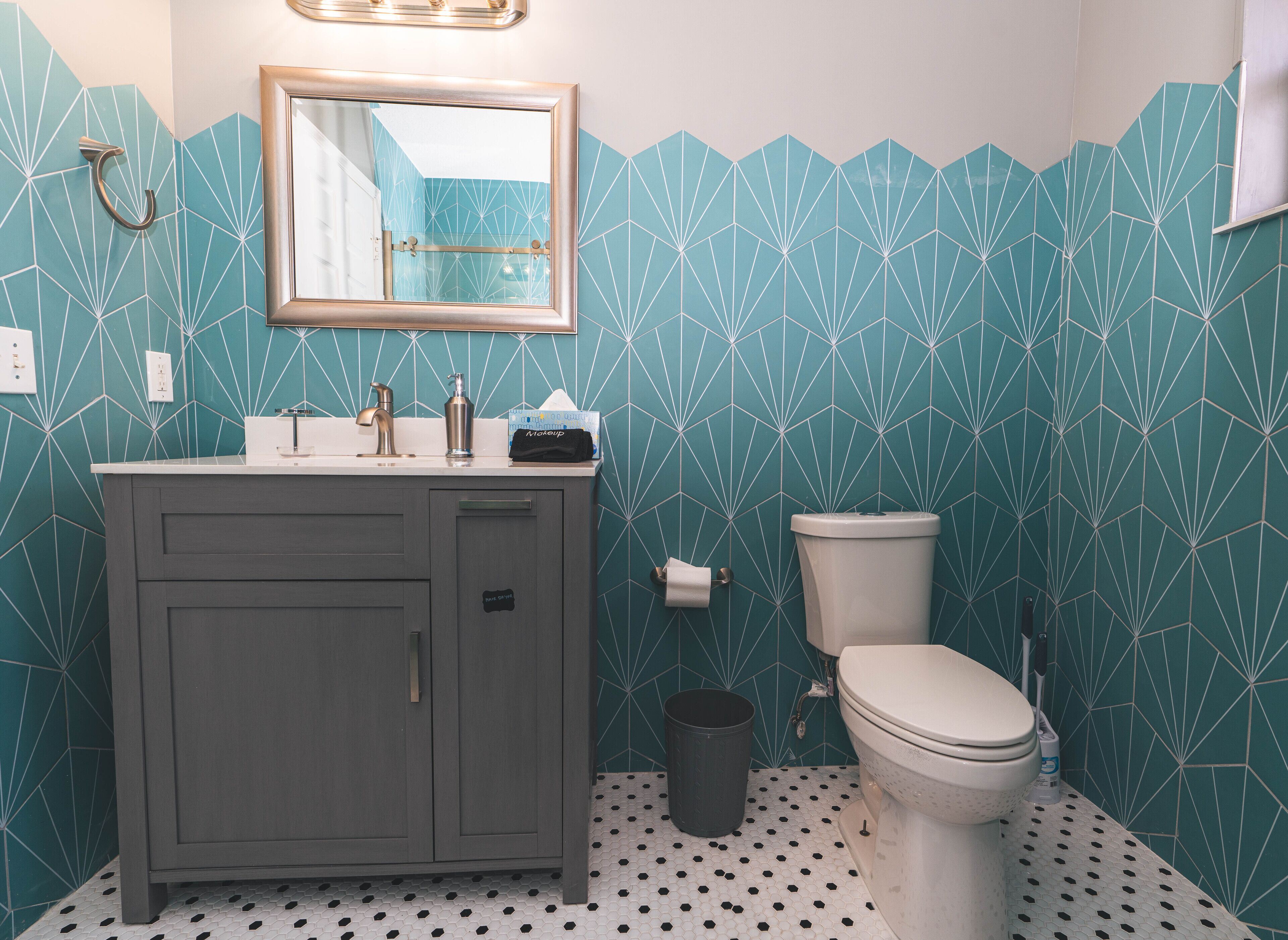A bathroom with a grey vanity, a toilet, and a mirror above the sink.